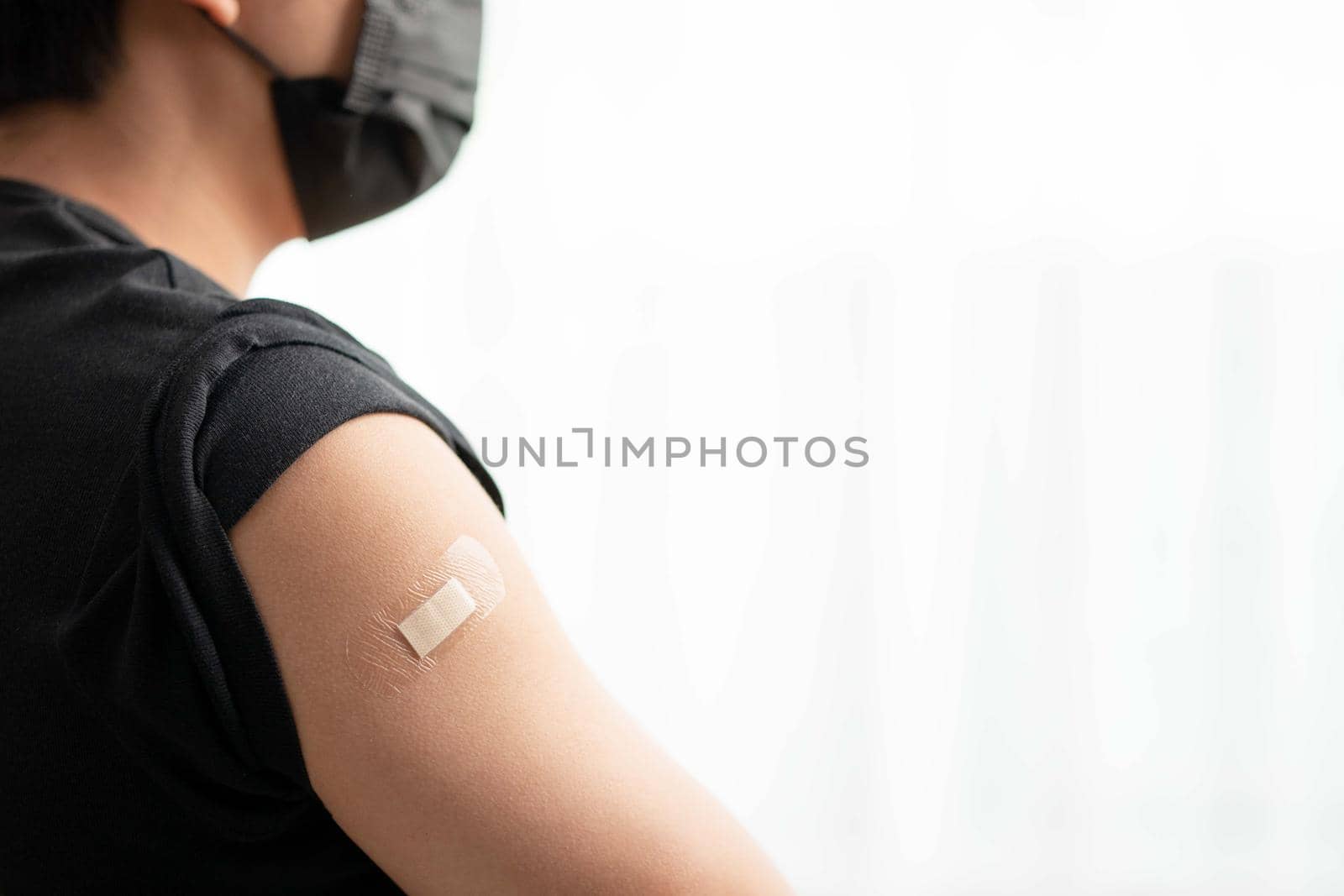 Man wearing mask arm with bandage showing his arm after receiving vaccine.