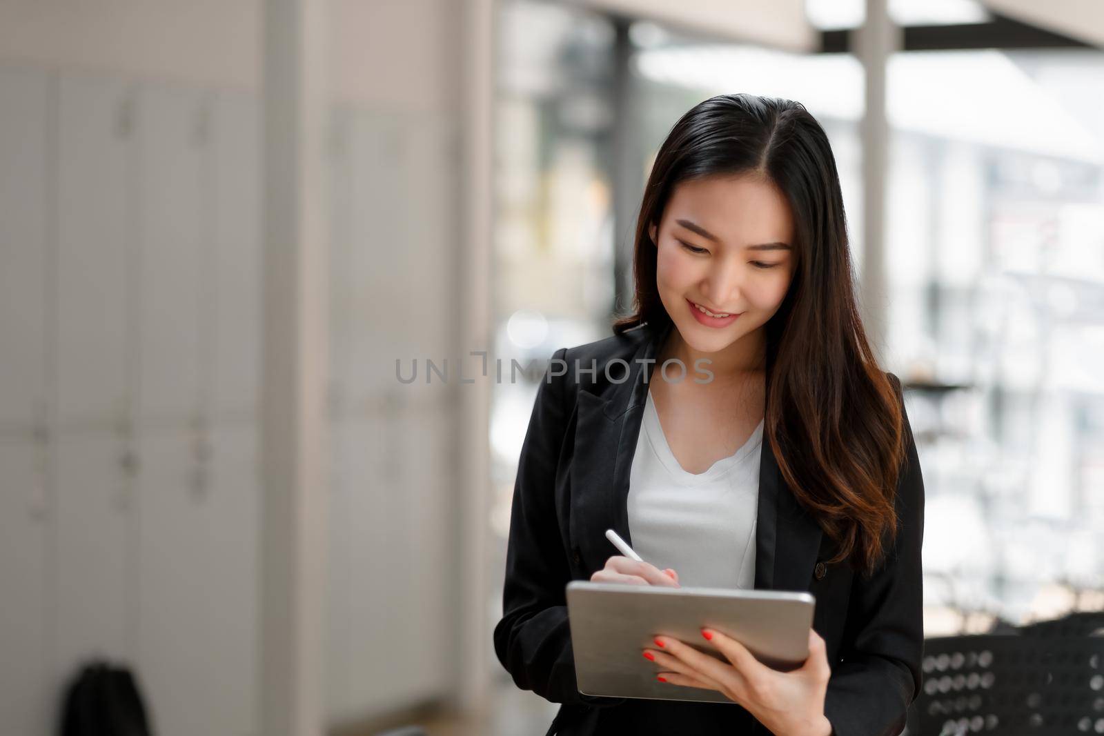 portrait of asian business woman usgin digital tablet in company meeting room by nateemee