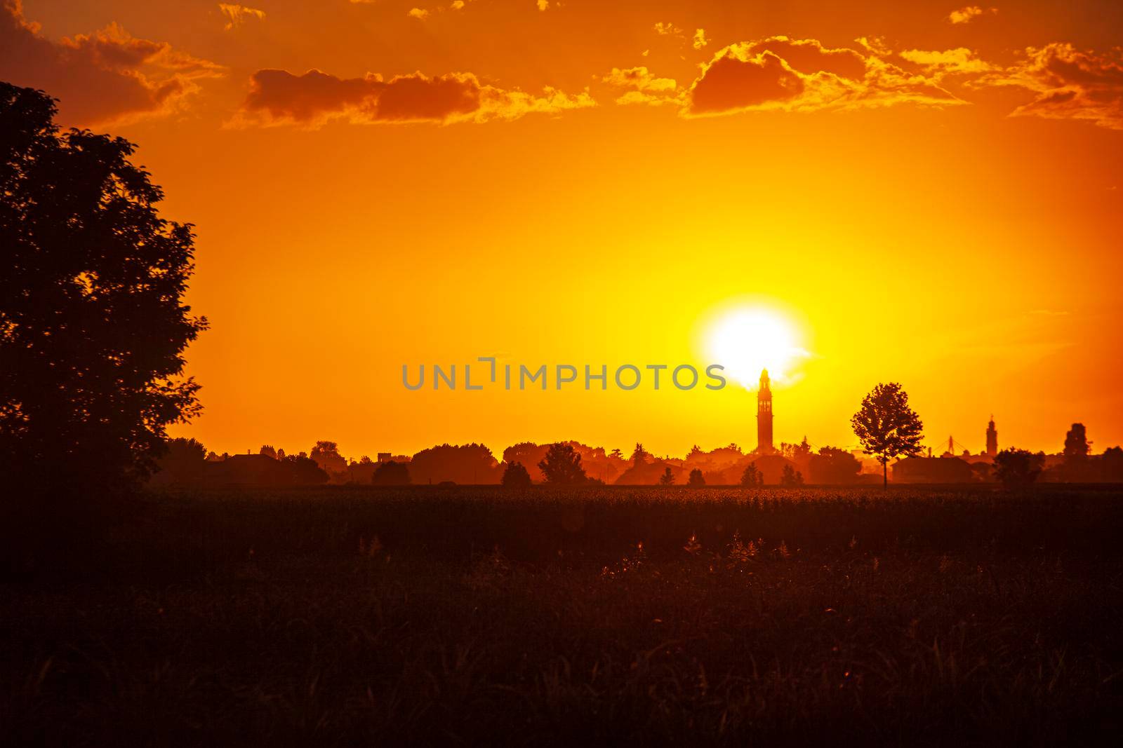 Sunset in a landscape with bell tower, trees and countryside