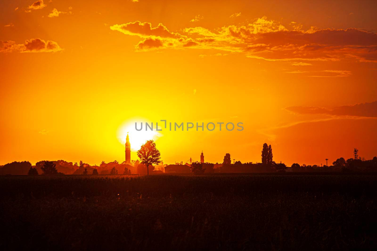 Sunset in a landscape with bell tower, trees and countryside