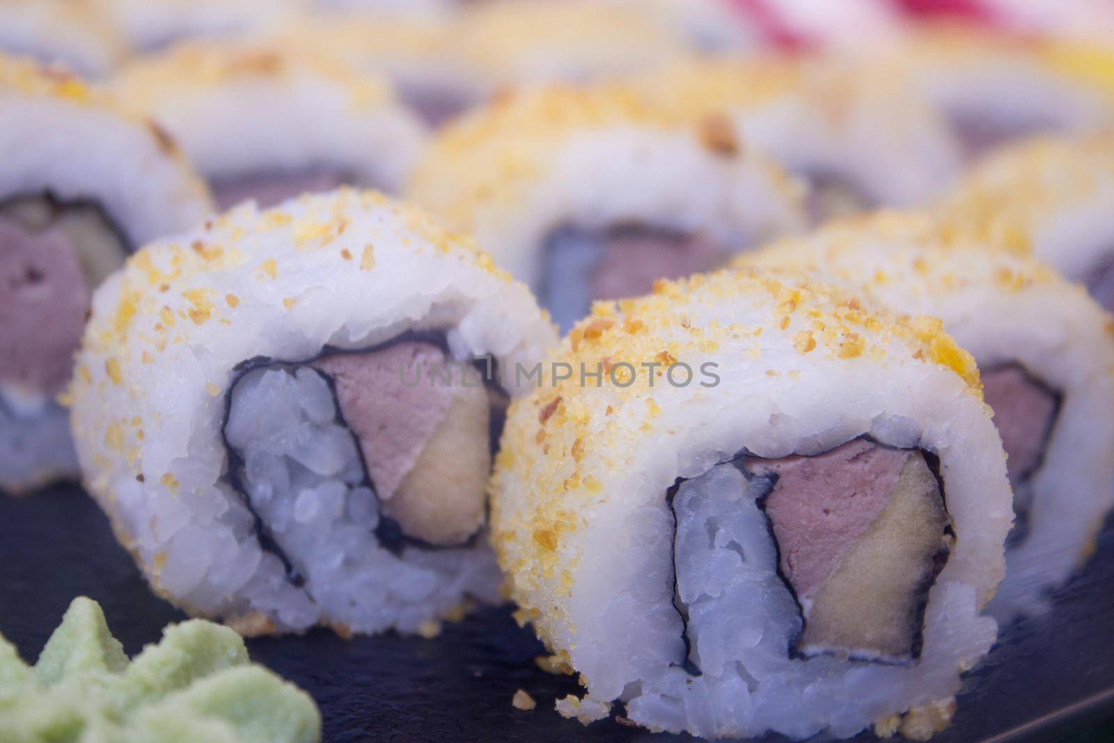 Assorted sushi food on a black slate plate. No people