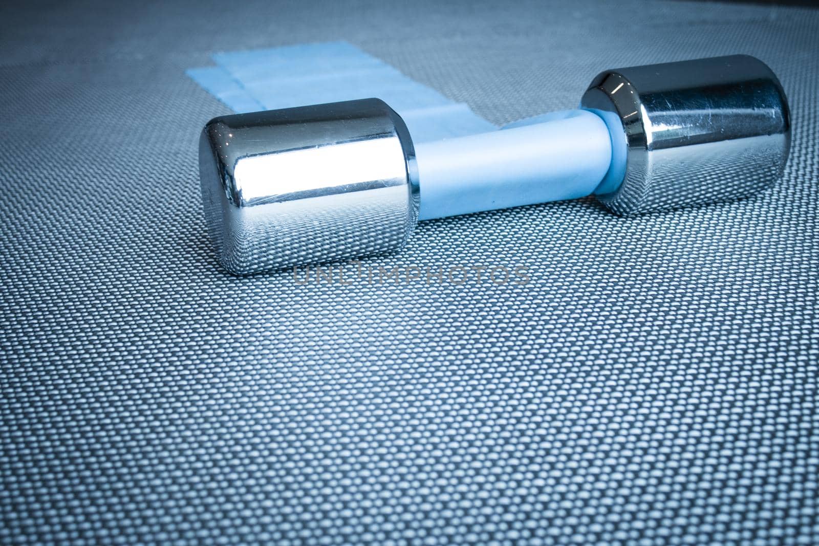 Silver dumbbell next to elastic band for pilates exercises. No people
