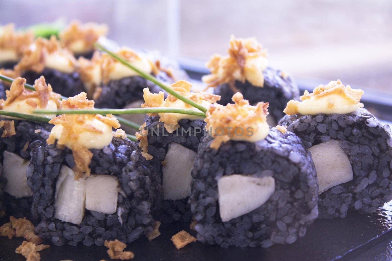 Assorted sushi food on a black slate plate. No people