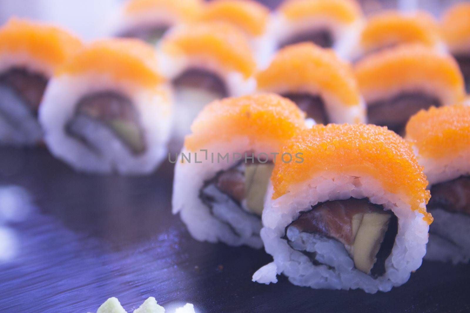 Assorted sushi food on a black slate plate. No people