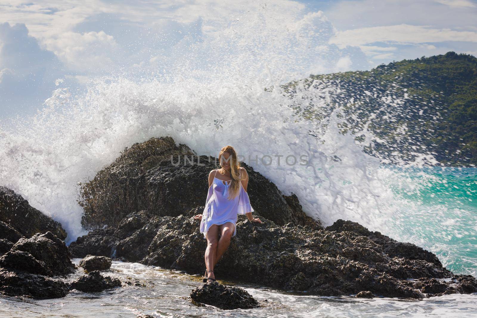 A young girl with long hair sits on a stone by the sea. by Yurich32