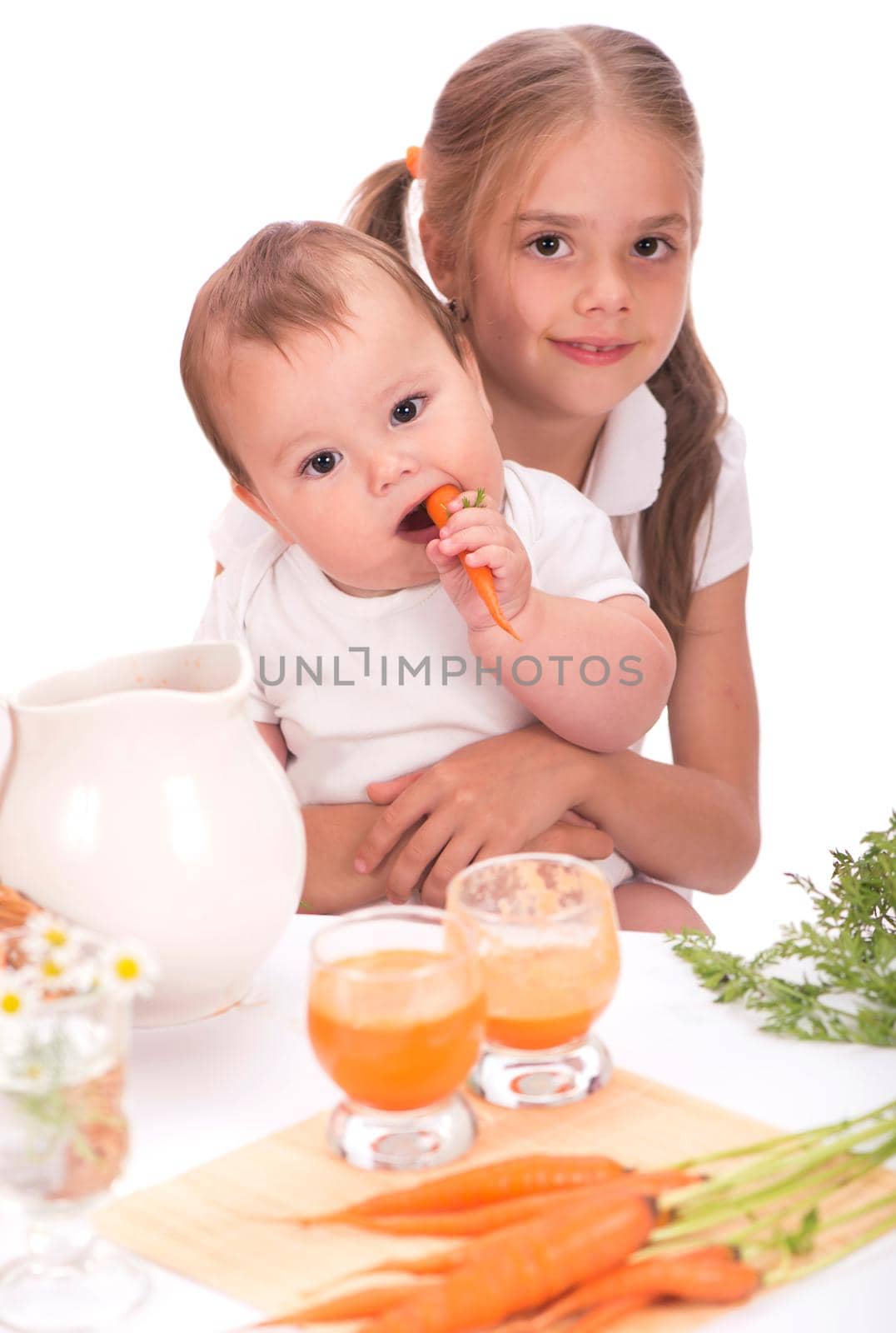 Girl and a little boy, brother and sister and carrot juice isolated on white background by aprilphoto