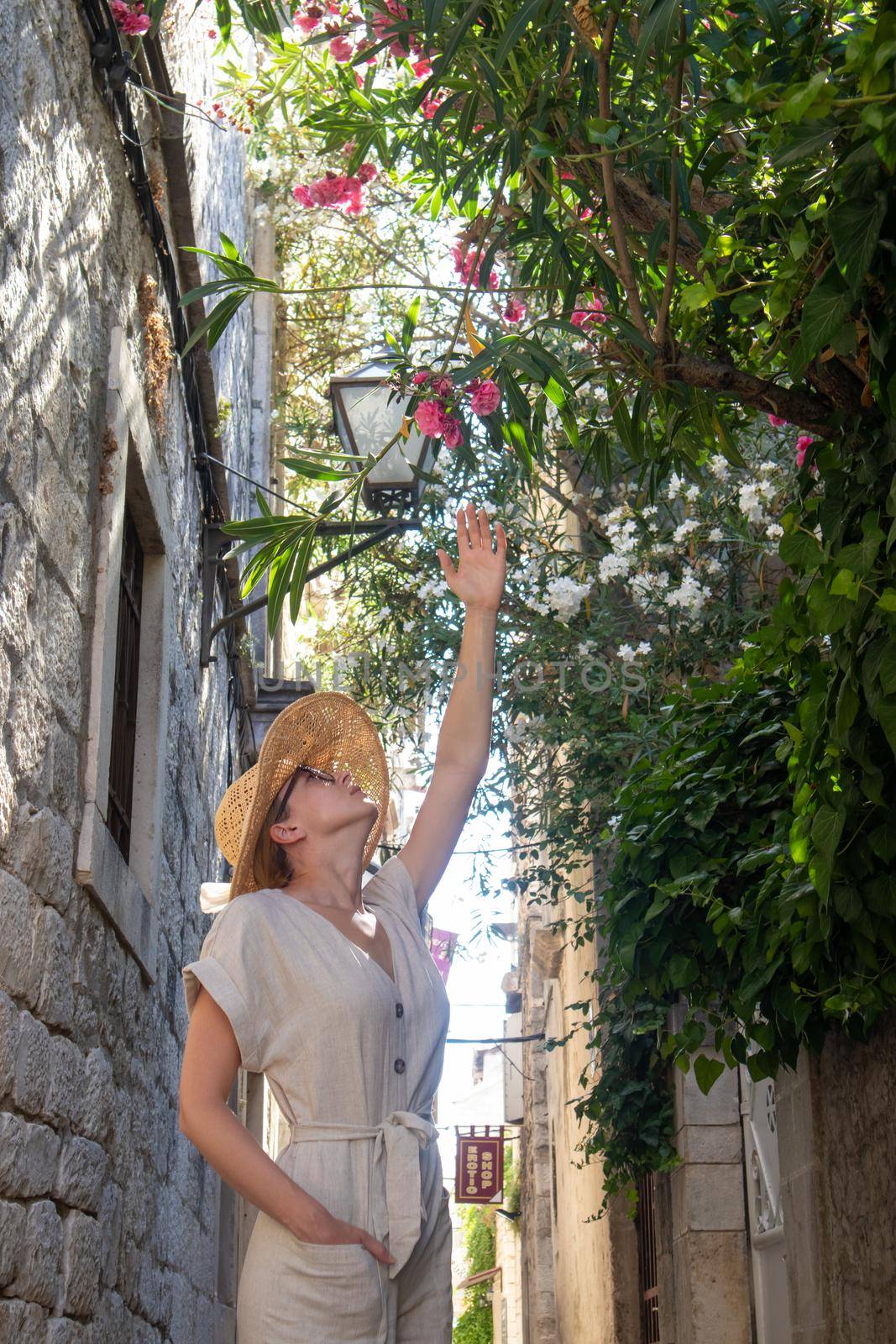 Beautiful blonde young female traveler wearing straw sun hat sightseeing and enjoying summer vacation in an old traditional costal town at Adriatic cost, Croatia