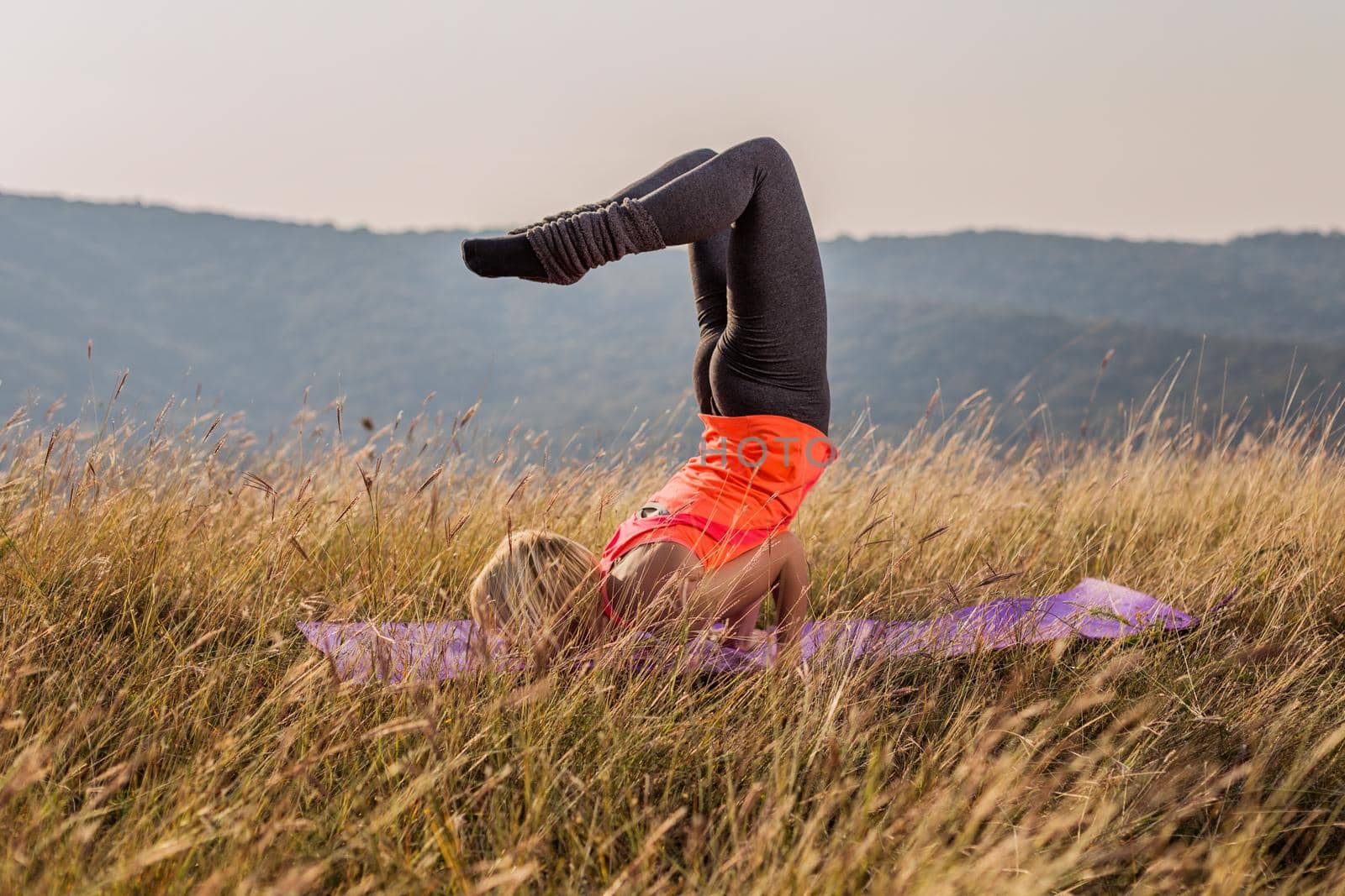 Beautiful woman doing yoga in the nature,Vrschikasana / Scorpion pose.Image is intentionally toned.