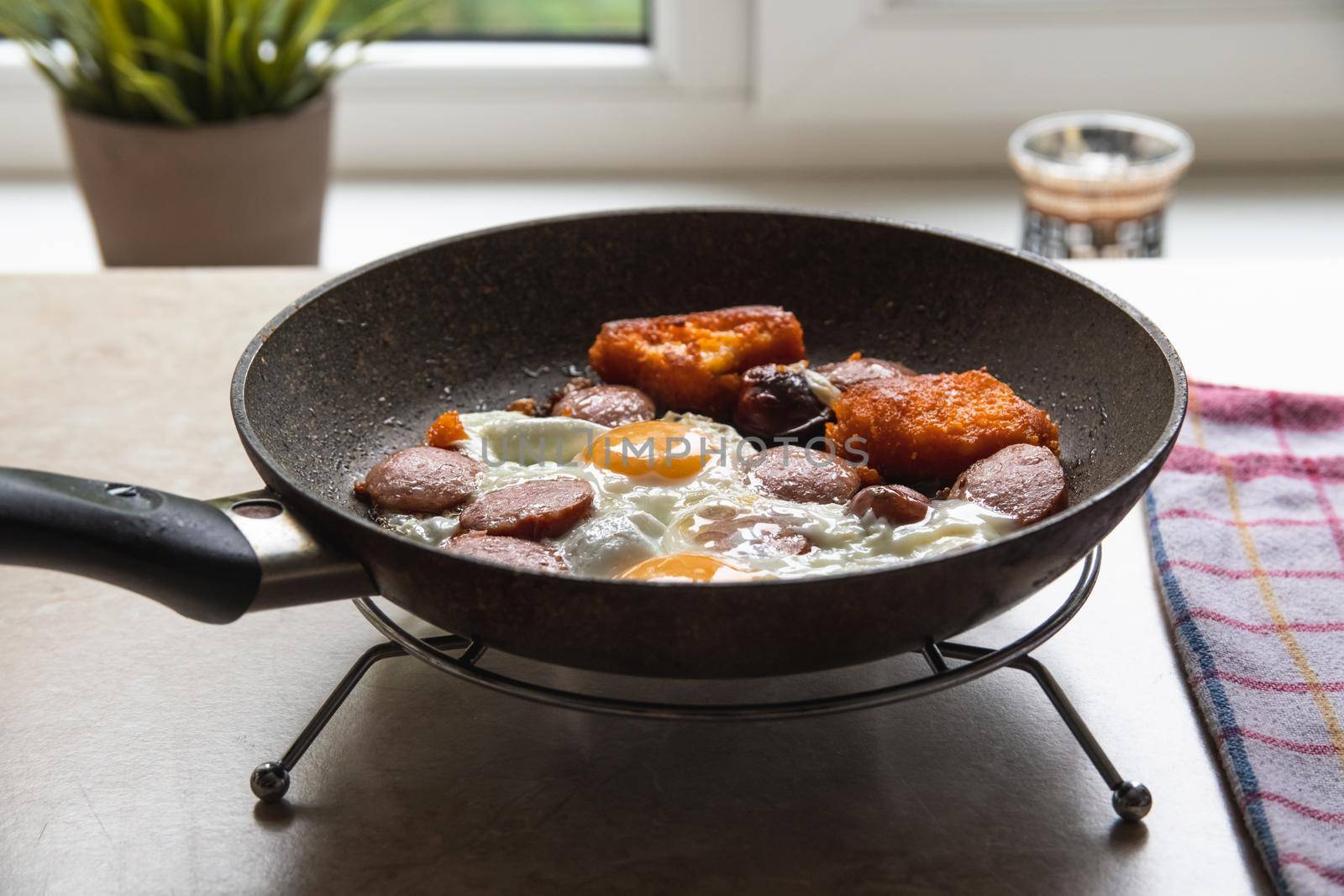 Barchelor breakfast - fried eggs with sausages on a teflon frying pan by Estival