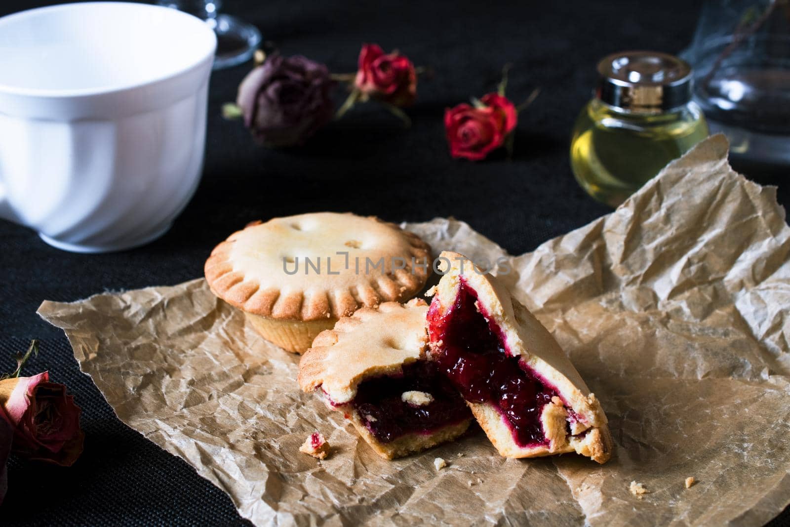 Cookies with jam on brown paper on black backgroung with white cup