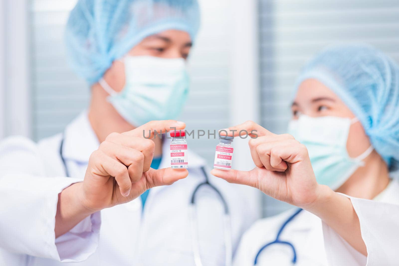 woman doctor or scientist in uniform wearing a face mask showing up coronavirus vaccine by Sorapop