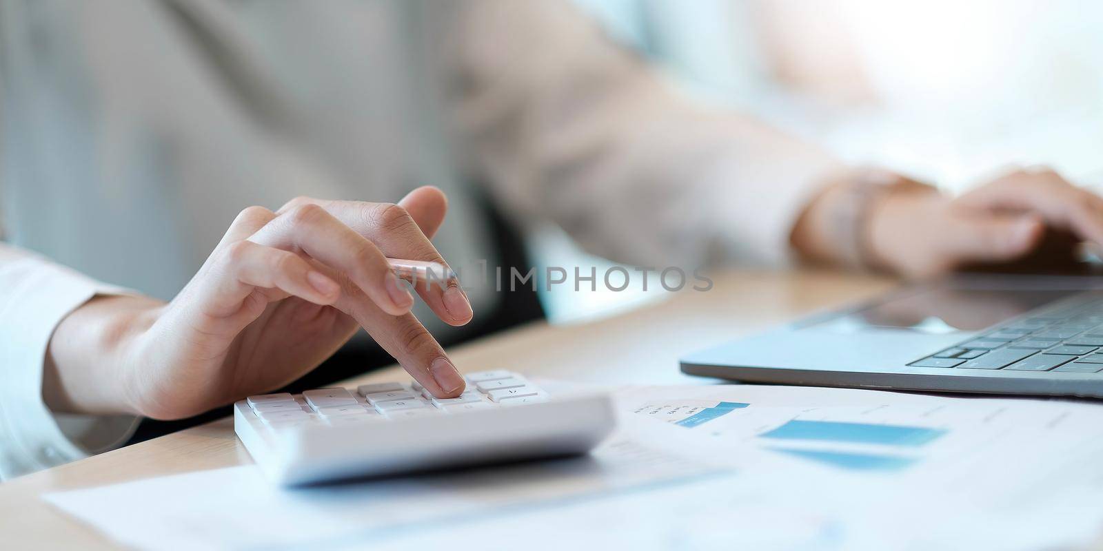 Close up Business woman using calculator and laptop for do math finance on wooden desk in office and business working background, tax, accounting, statistics and analytic research concept.