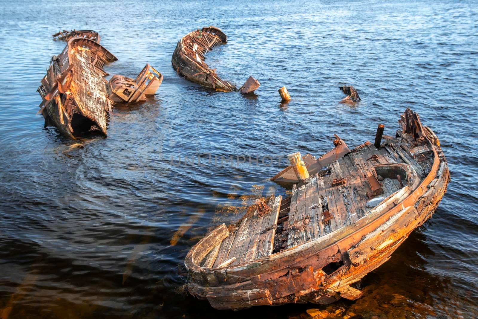 Rusty old abandoned wooden fishing boat which is pulled out on the coast of the sea in Teriberka