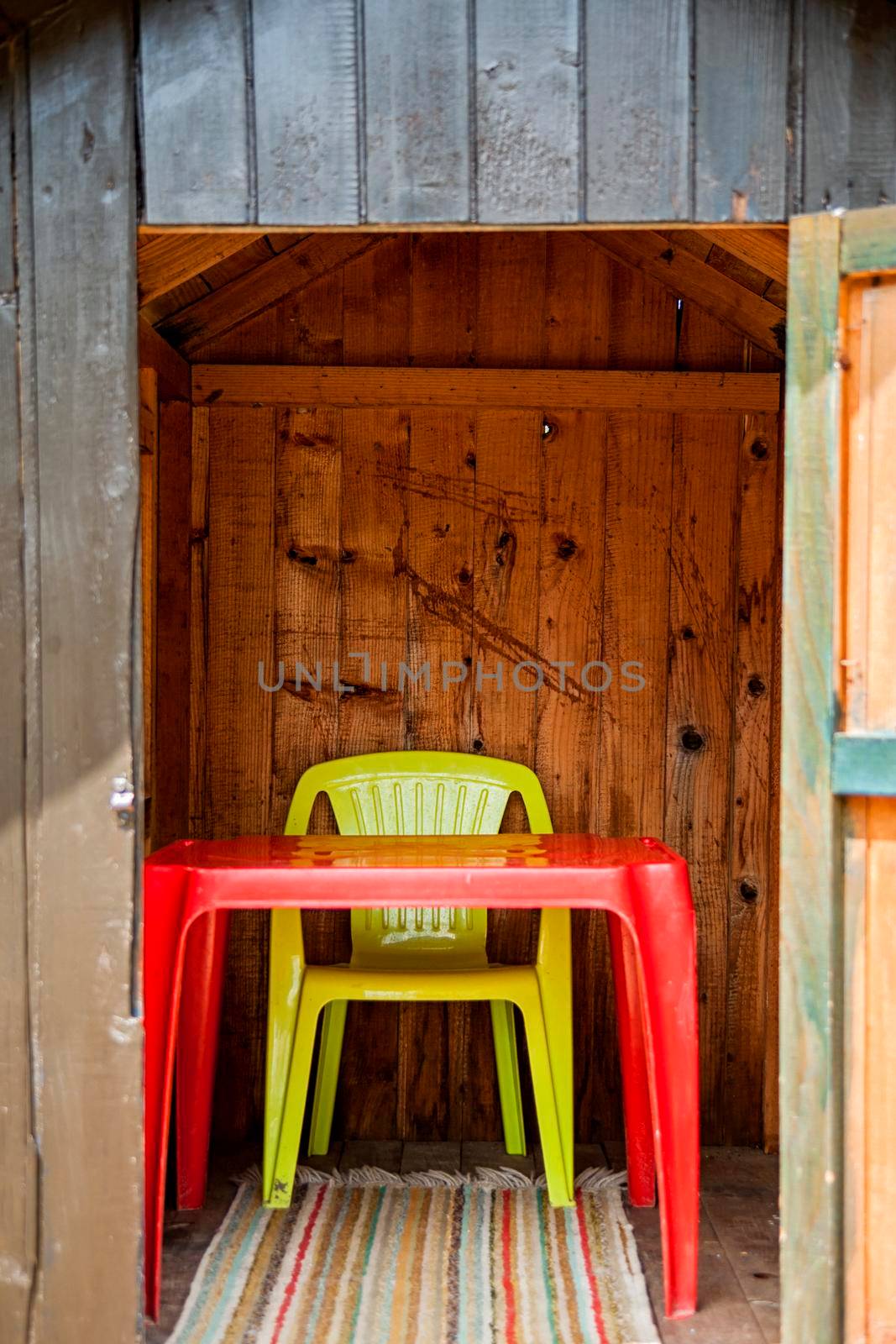 Inside of the childrens plsyig hut. There is a room only for red plastic table and yellow chair.