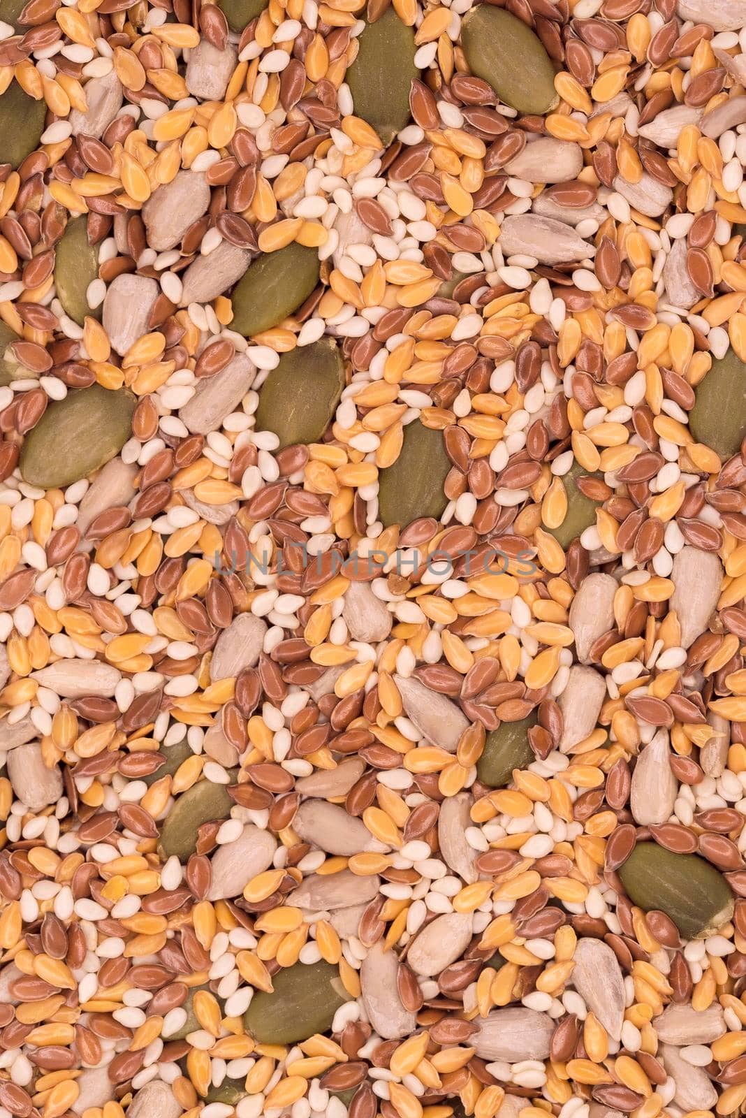 Surface of a flat seeds with sesame, flax, pumpkin and sunflower seeds, vertical top view close-up, background