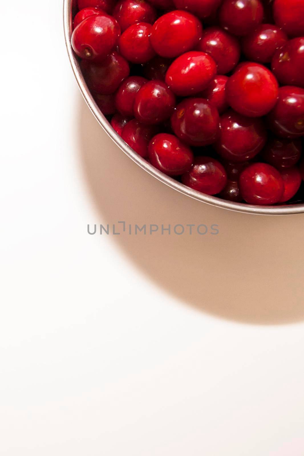 Bowl of cherries on a white background. Red cherries. Bowl placed on top lright corner of the frame