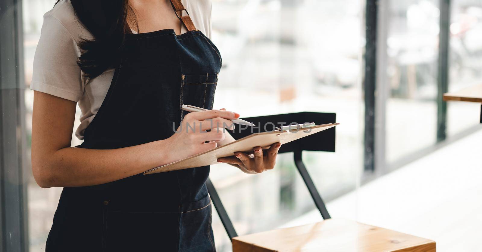 Close up female waitress take order cafe restaurant visitors couple, friendly professional woman server wear apron write dinner food menu choice, serving staff good customer service