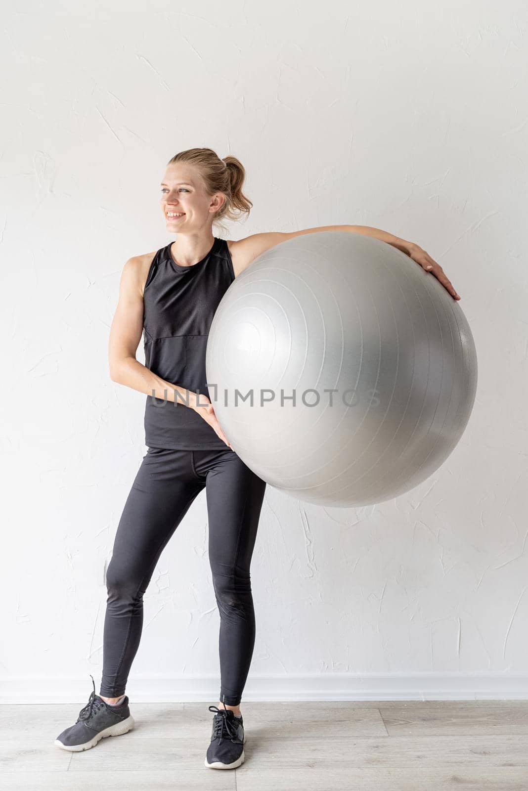 Sport and healthy lifestyle concept. Portrait of a young smiling sportive woman holding fitball