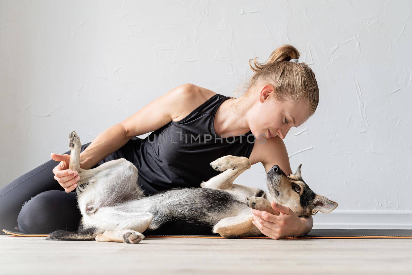 Sport and healthy lifestyle concept. Young sportive woman embracing her mixed breed dog laying on the floor at home