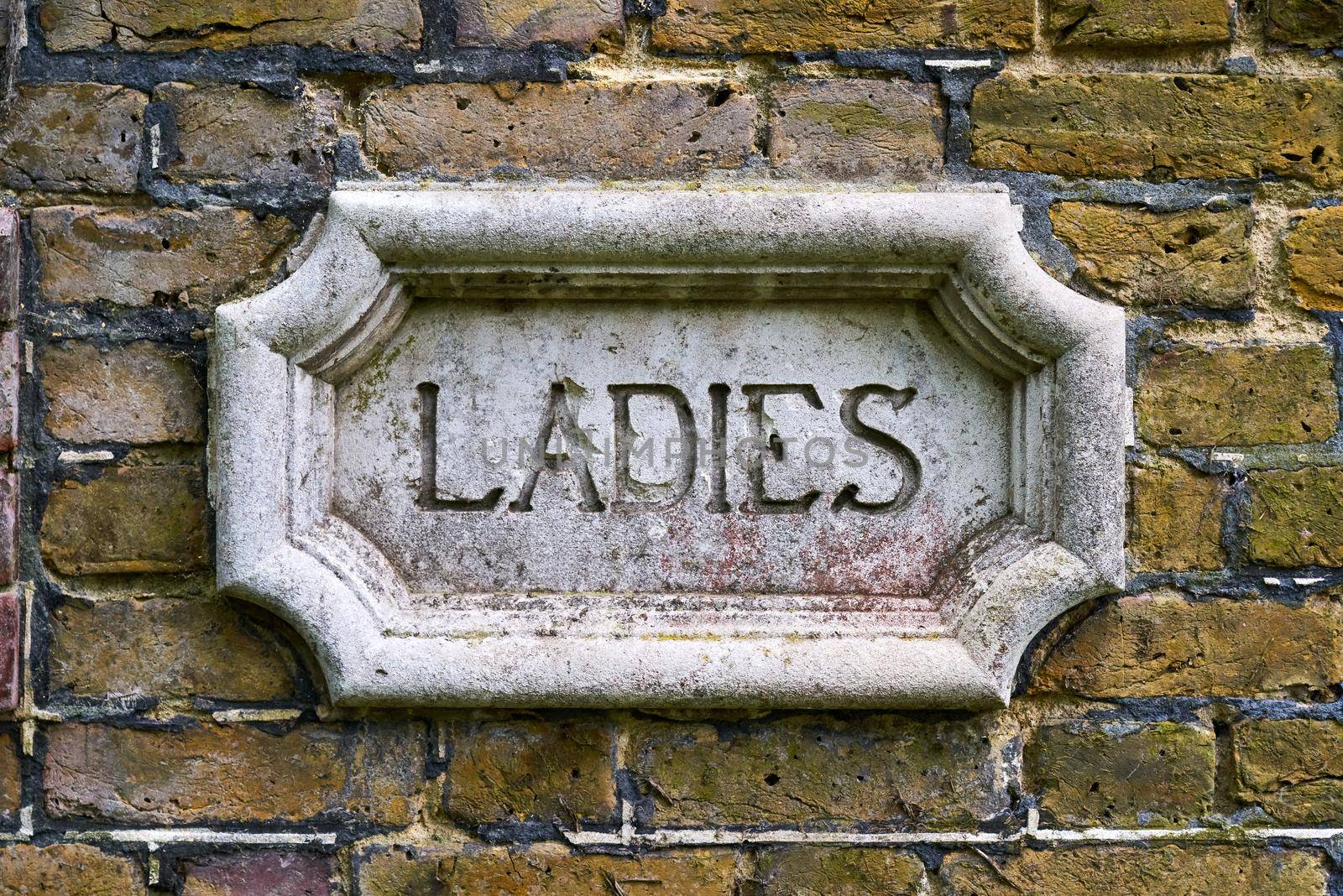 An elaborate sign for the toilet on an external brick wall