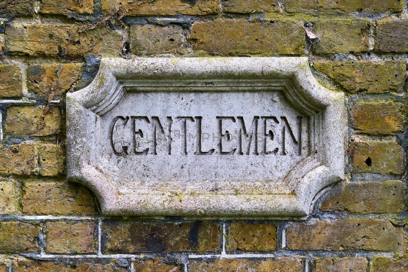 An elaborate sign for the toilet on an external brick wall