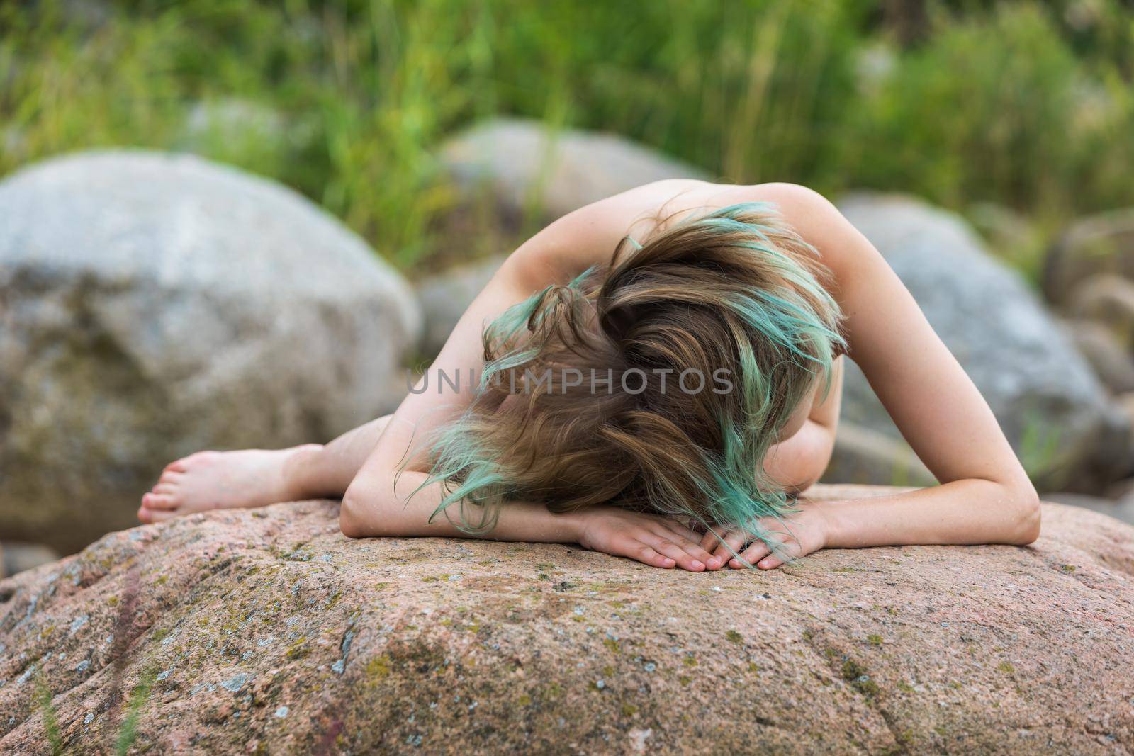 Lifestyle and beauty concept. Young nude woman enjoying nature among large stones by the sea. Naked woman on the seashore