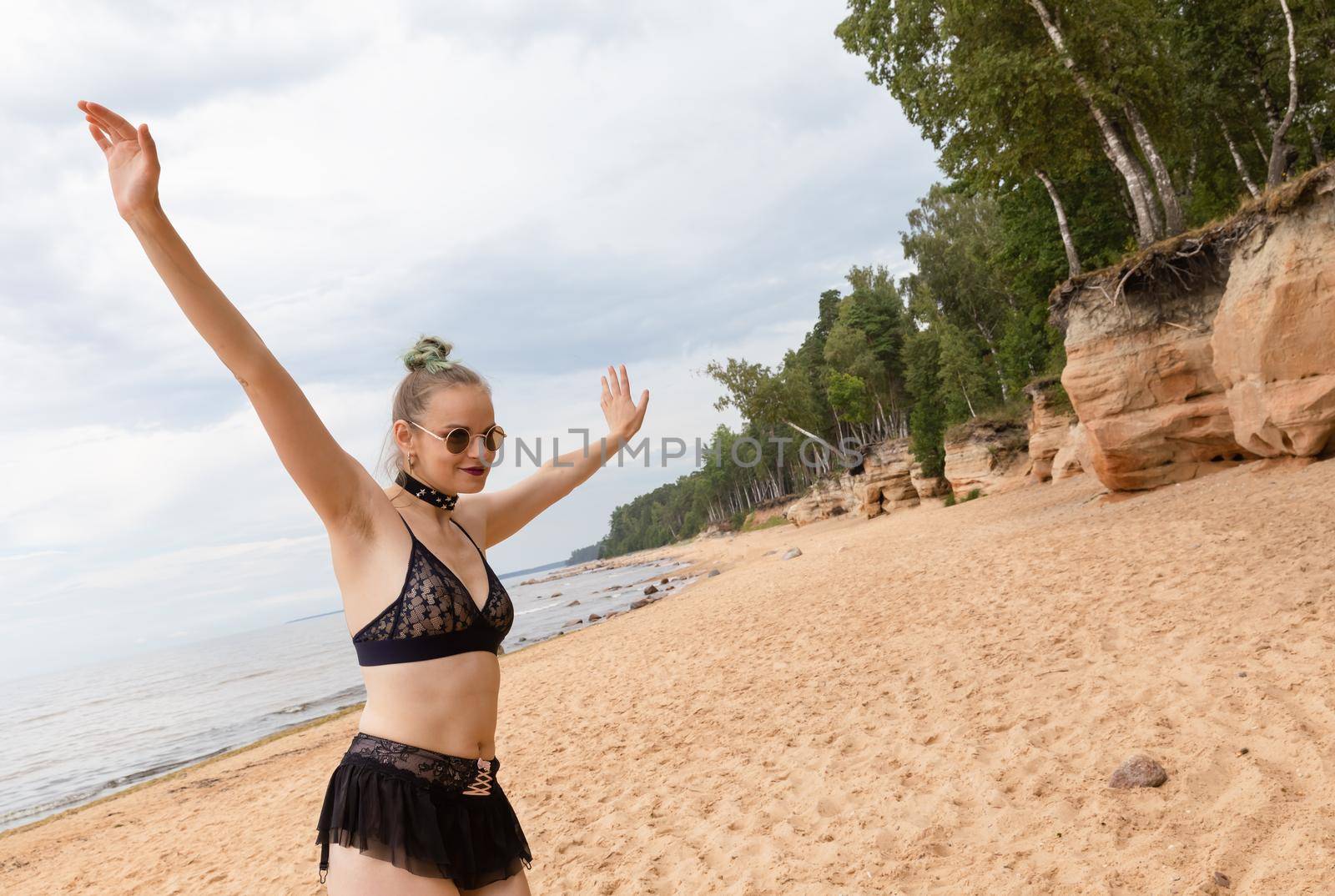 Beauty and healthy lifestyle. Young woman in black lingerie posing near the sandstone caves on the seashore. Shell rock caves.