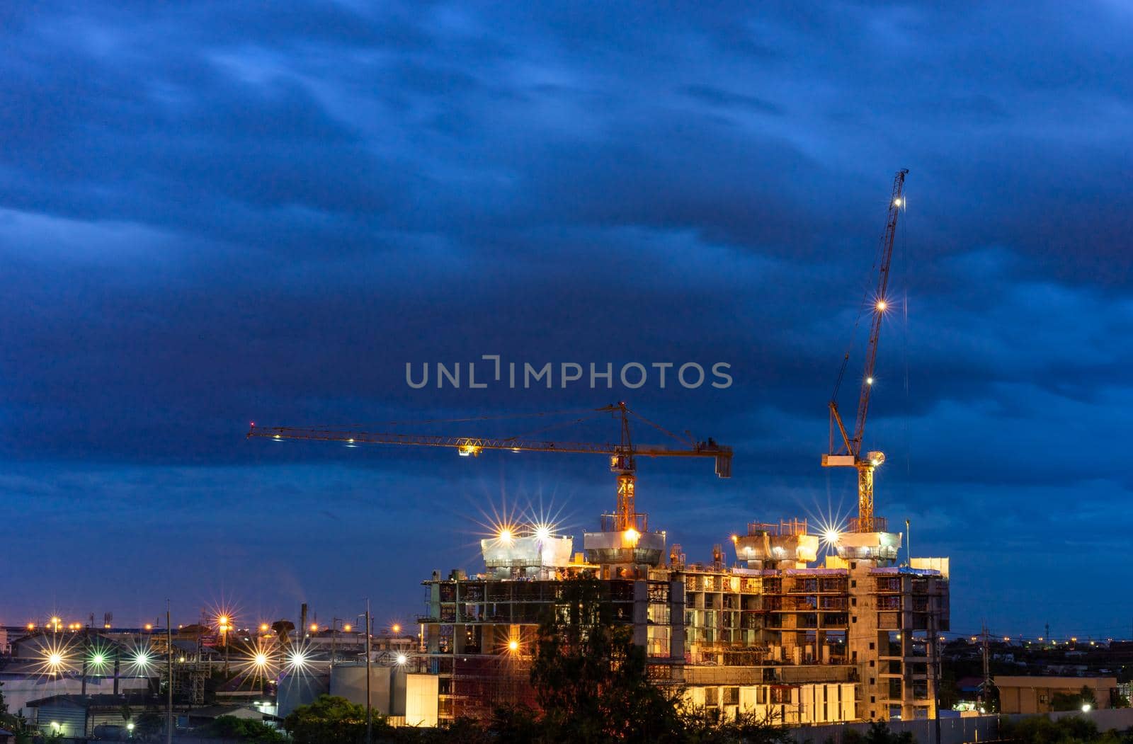 Construction site with cranes in cloudy night