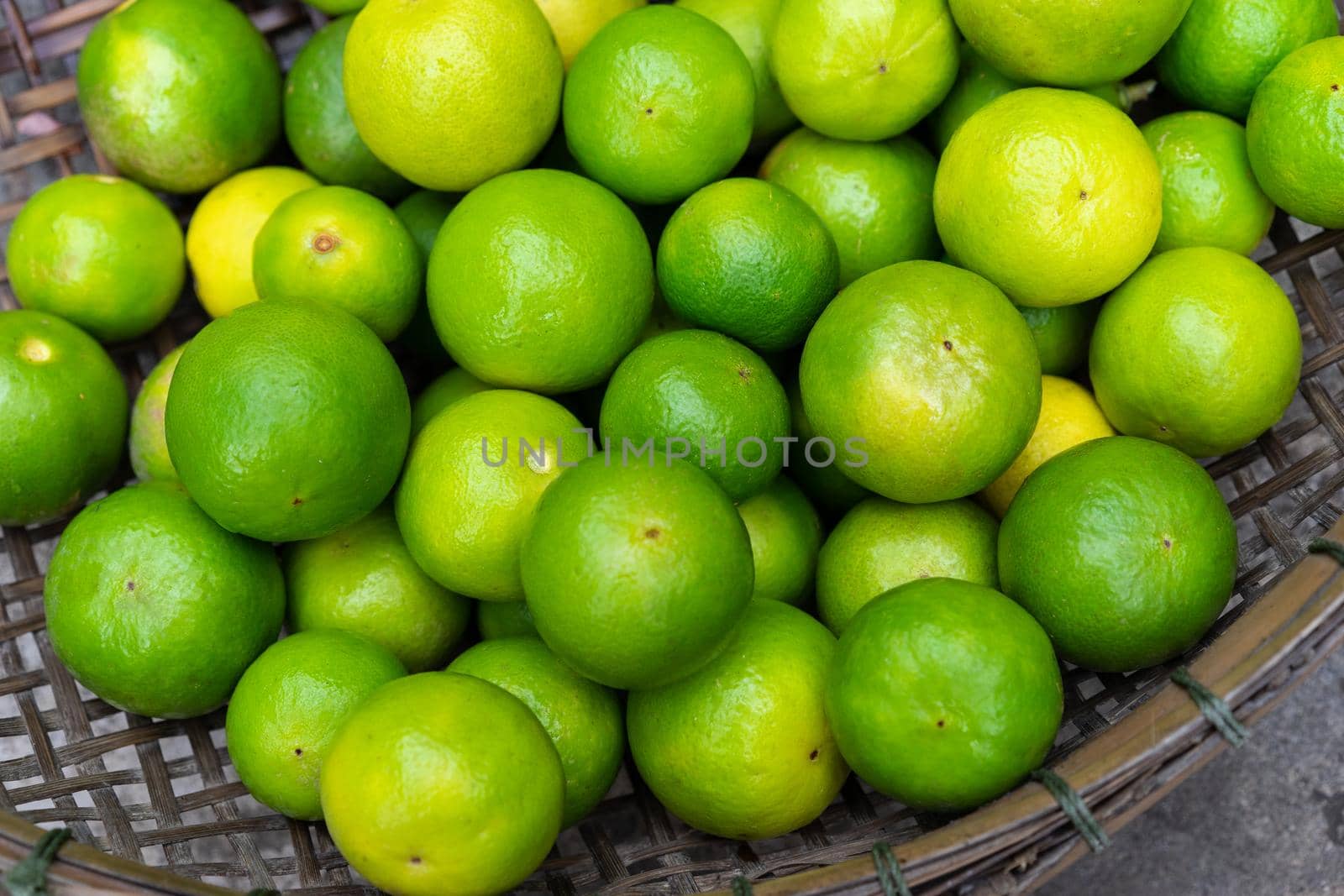 Fresh green limes in wooden basket for sell at the market by domonite