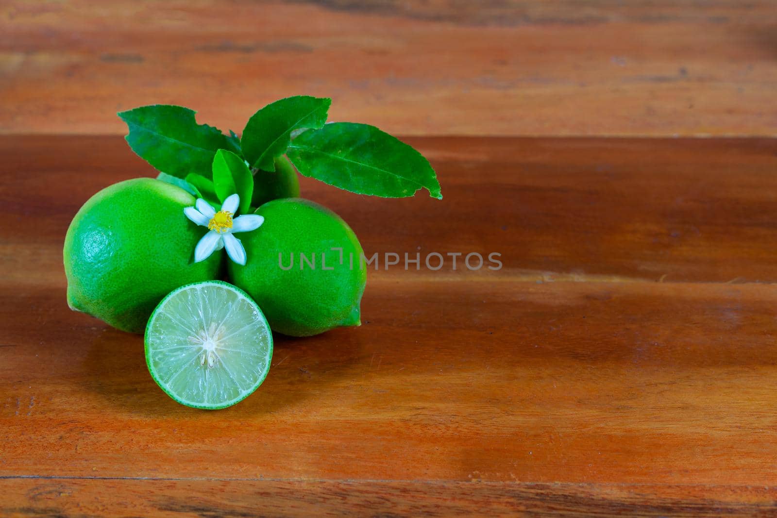 Flower, cut and whole limes on wooden background