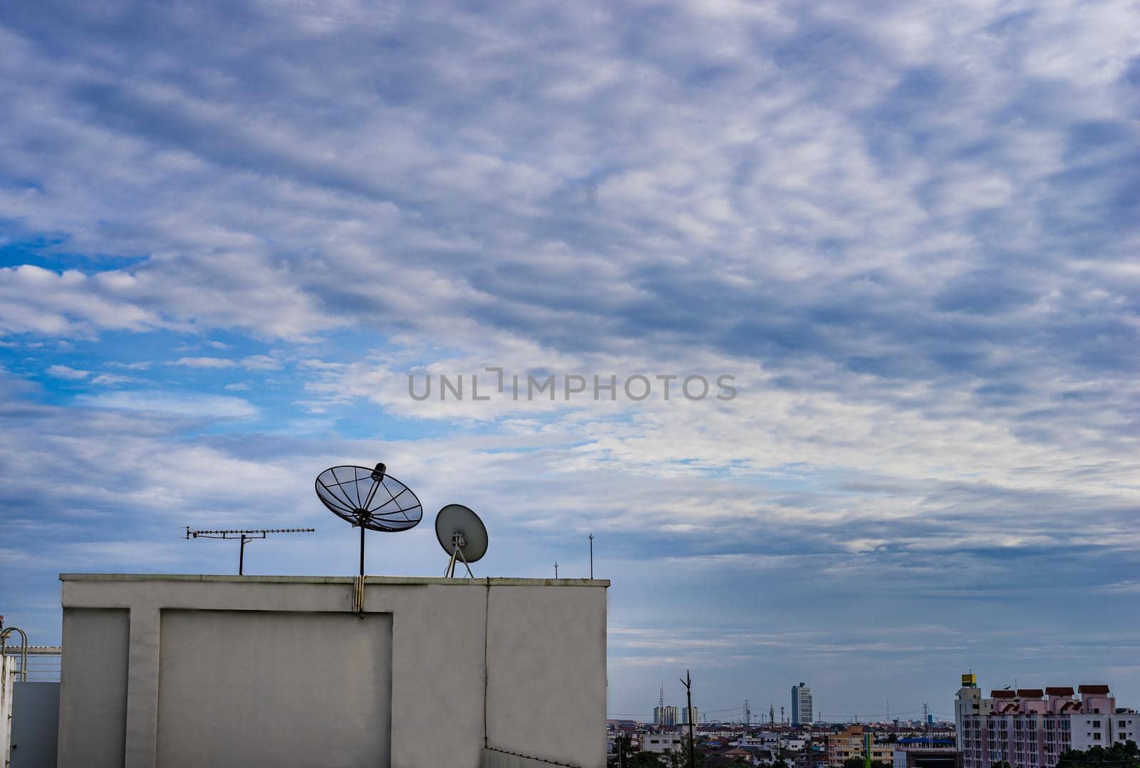 Satellite dish antenna on top of the building in urban area with cloudy sky