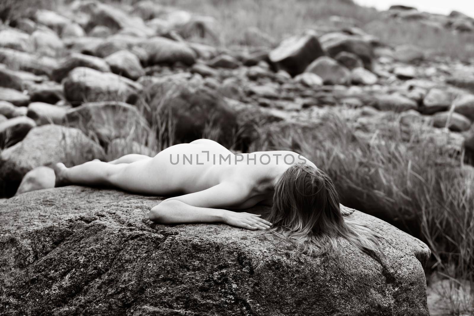 Nude woman enjoying nature among stones by the sea by palinchak