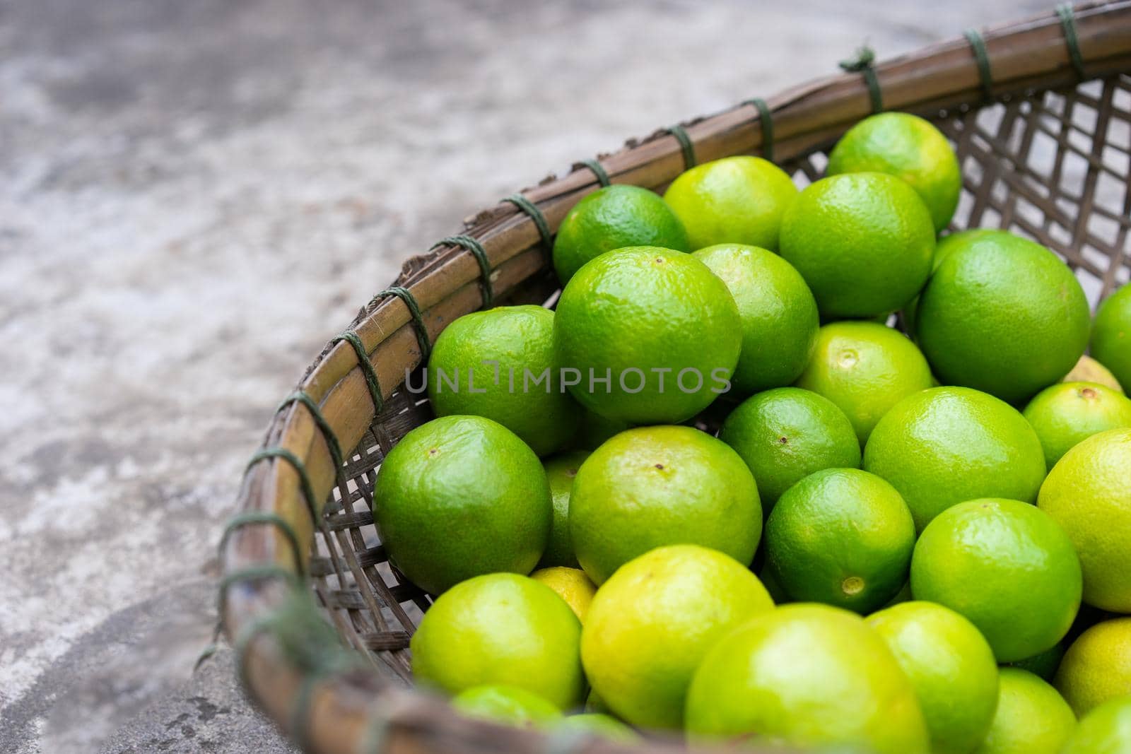 Fresh green limes in wooden basket for sell at the market by domonite