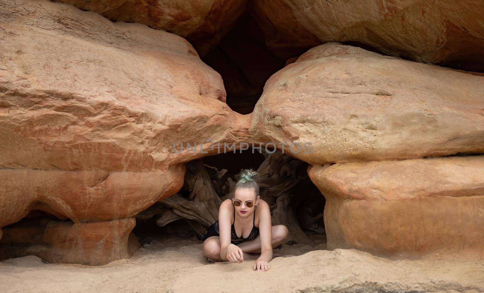 Beauty and healthy lifestyle. Young woman in black lingerie posing near the sandstone caves on the seashore. Shell rock caves.