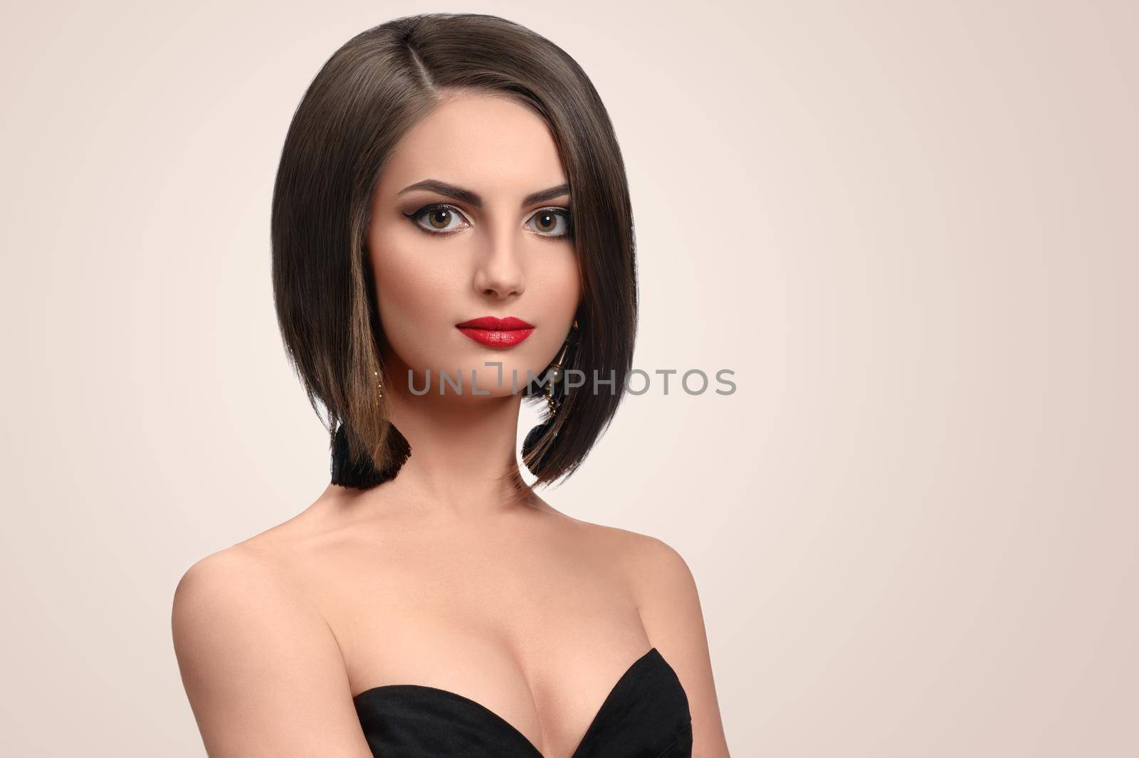 Young grace. Elegant young woman in a black dress smiling softly to the camera posing in a black dress on beige background copyspace skincare cosmetology hair therapy treatment salon fashion concept