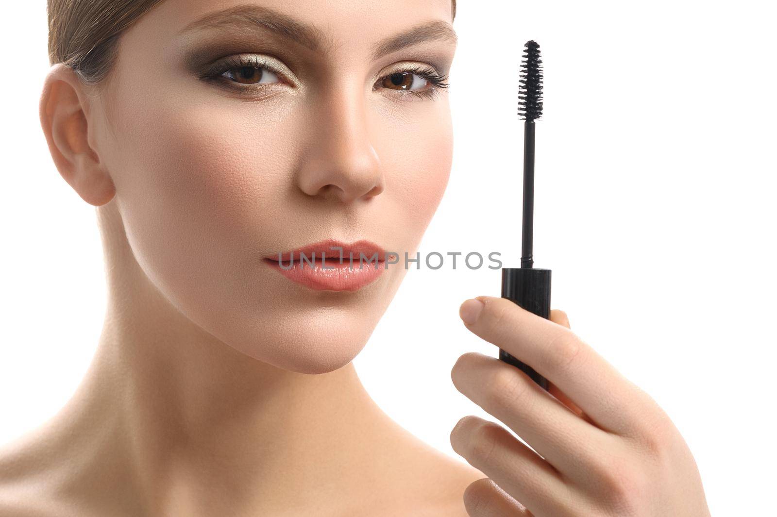 Armed for perfect makeup. Close up cropped studio shot of a beautiful young woman smiling confidently holding mascara brush in her hand isolated on white fashion beauty profession fashionable stylish