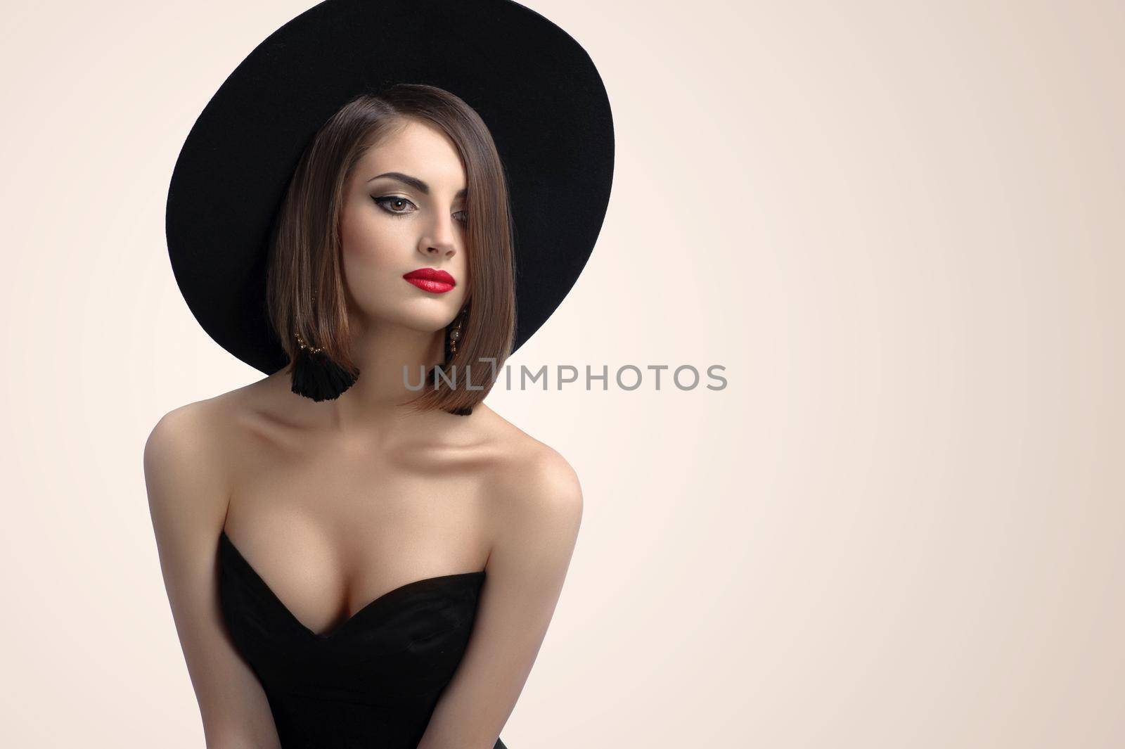 Elegant fashionable woman posing wearing a hat in studio by SerhiiBobyk
