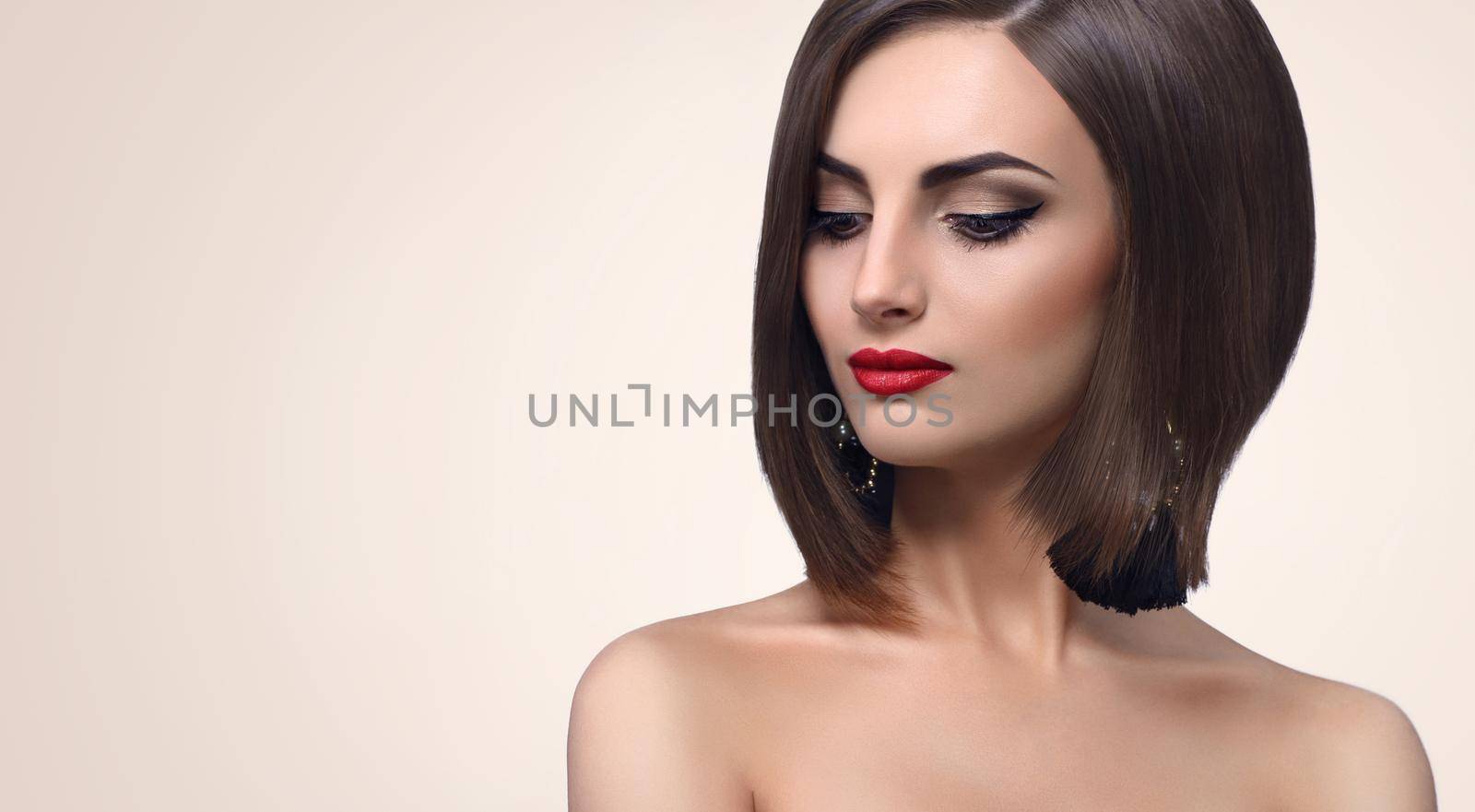 Young fashion model posing sensually looking away wearing black dress and evening makeup with red lips and smoky eyes copyspace beauty fashion style elegance cosmetics concept.