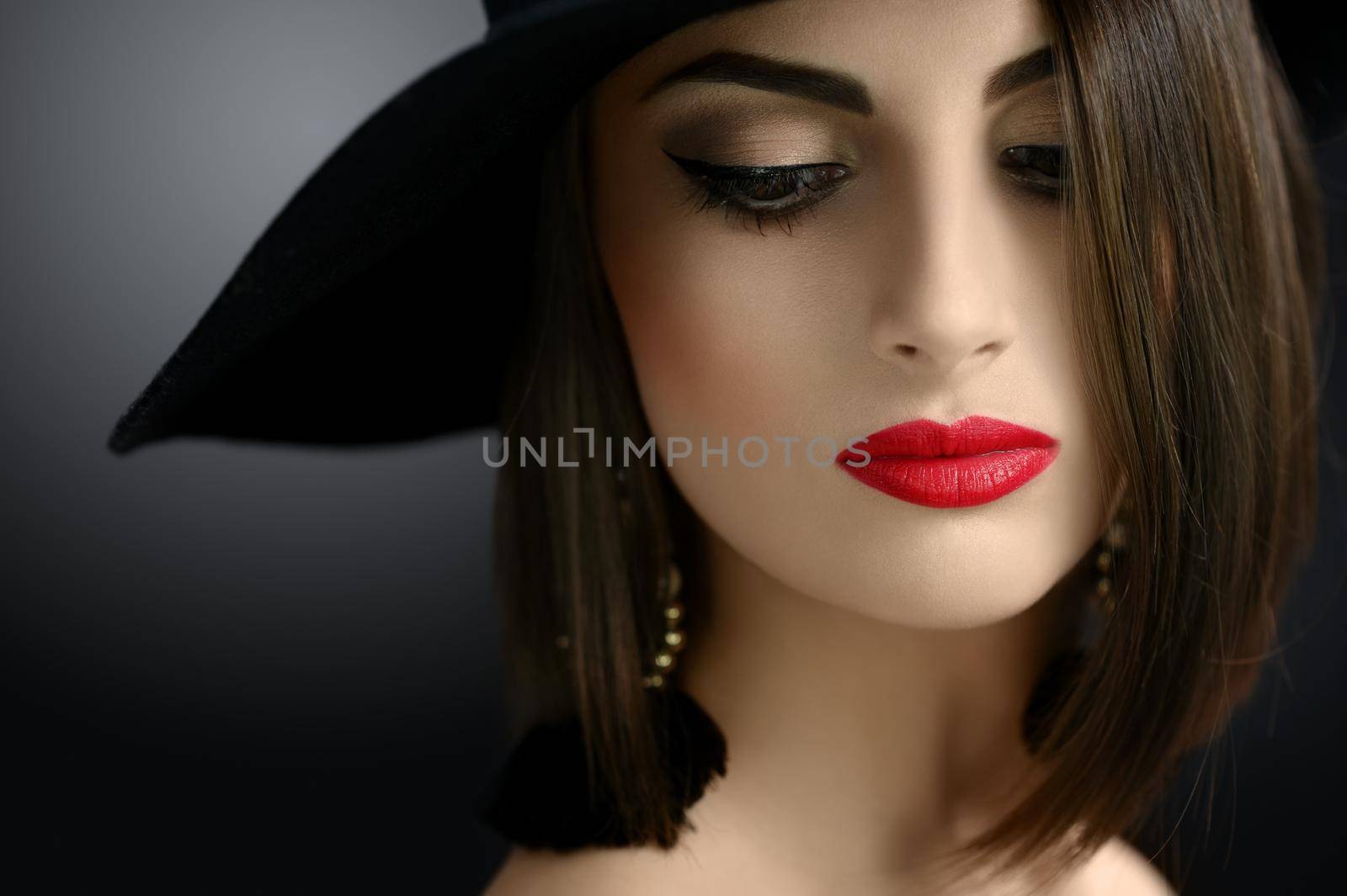 Cropped close up of a sexy red lipped elegant brunette in a hat posing sensually looking away beauty makeup cosmetics red lips seduction seductive retro vintage luxury fashion classy concept.