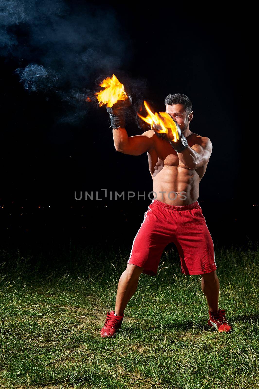 Powerful male boxer training outdoors with his boxing gloves bur by SerhiiBobyk