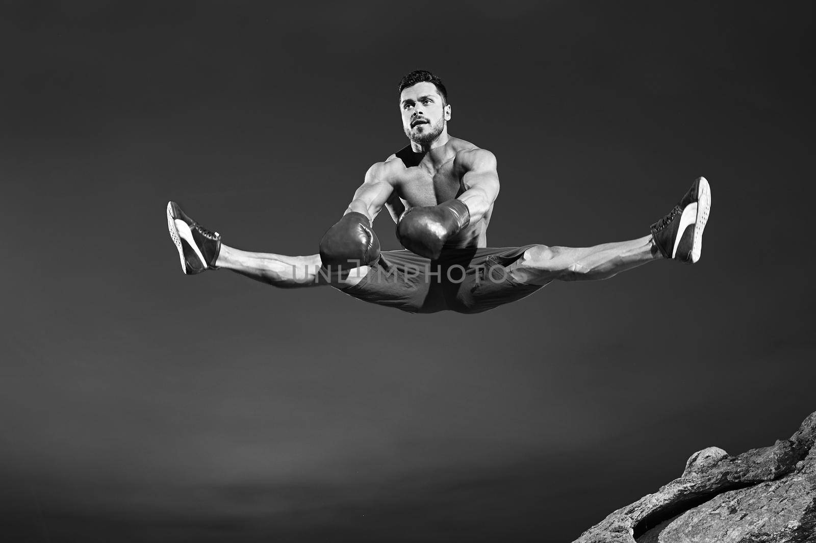 Male athlete doing splits in the air while jumping by SerhiiBobyk