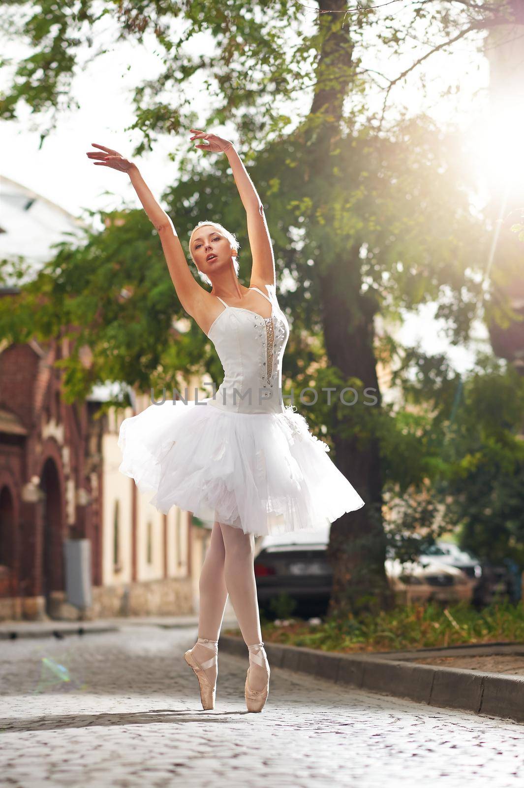 Vertical shot of a beautiful ballerina dancing on the street of an old town on a beautiful sunny warm day outdoors grace sensuality femininity beauty.