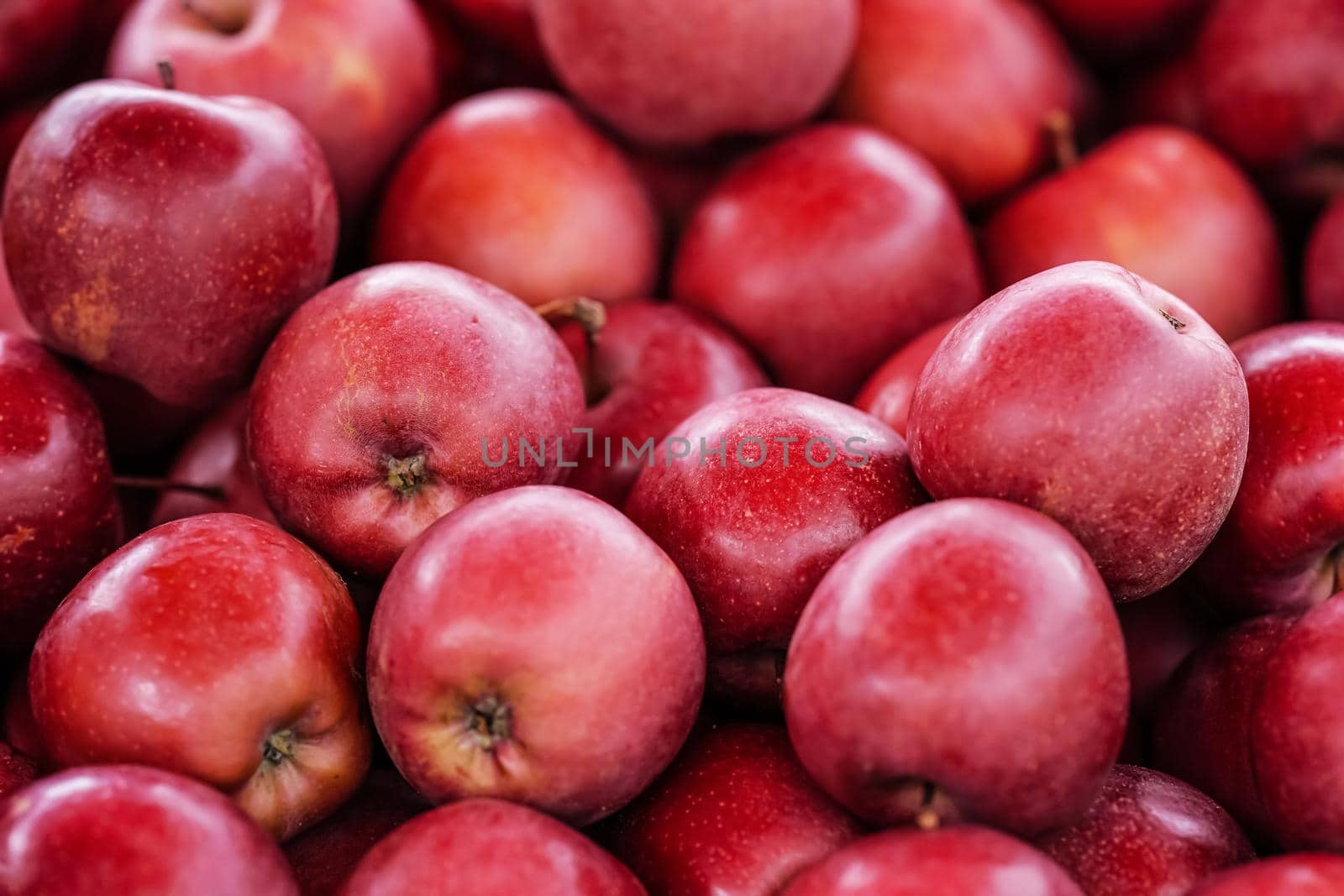 Glossy red apples displayed on street food market, closeup detail.