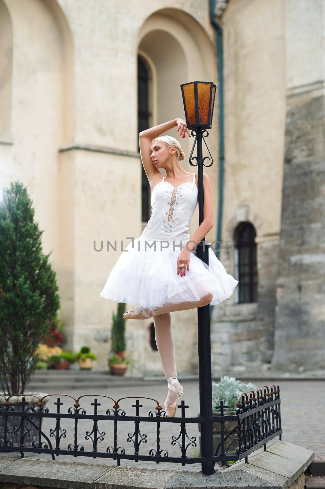 Vertical full length shot of a beautiful ballerina standing near street lamp looking away dreamily beauty urban city grace elegance