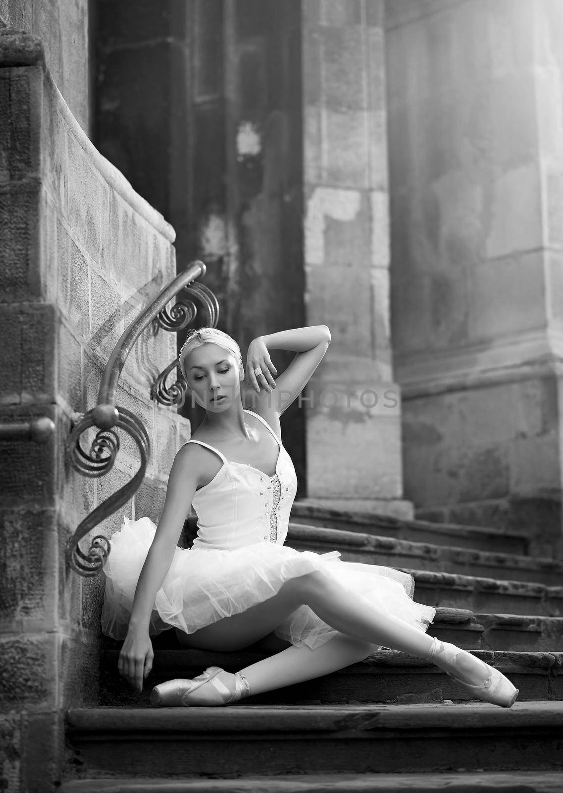 Embodying femininity. Monochrome shot of a beautiful ballerina sitting on stairs near an old building soft focus