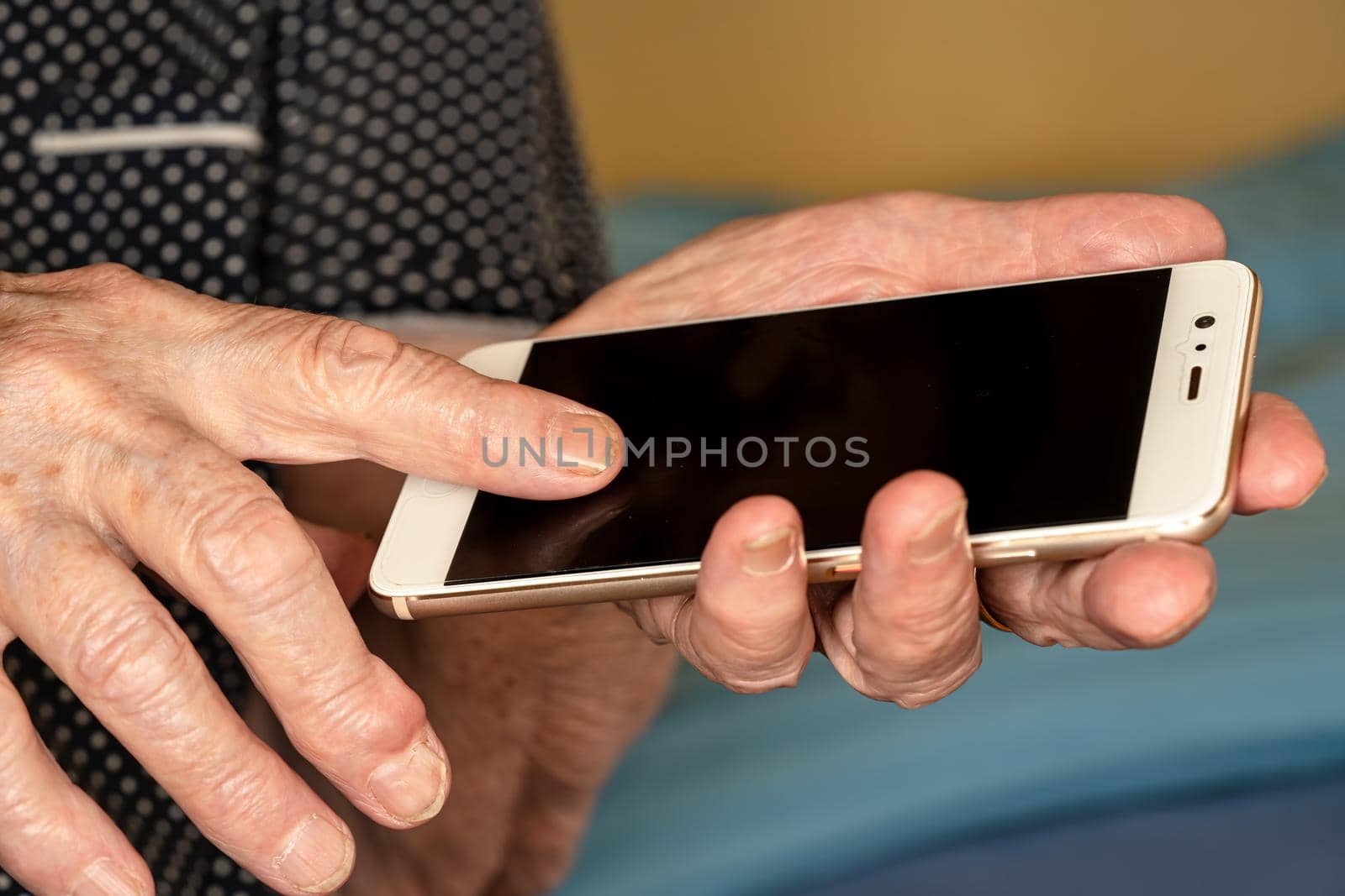 Elderly senior woman holding white mobile phone in her hands, closeup detail.