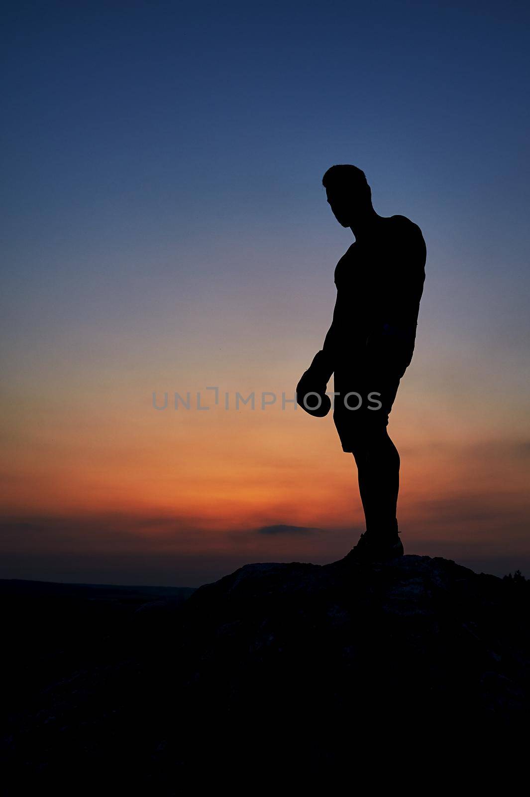 Silhouette of a man standing on top of a rock observing beautiful sunset copyspace anonymous mysterious nature skies sky dusk epic alone person loneliness beauty relaxation vitality harmony.