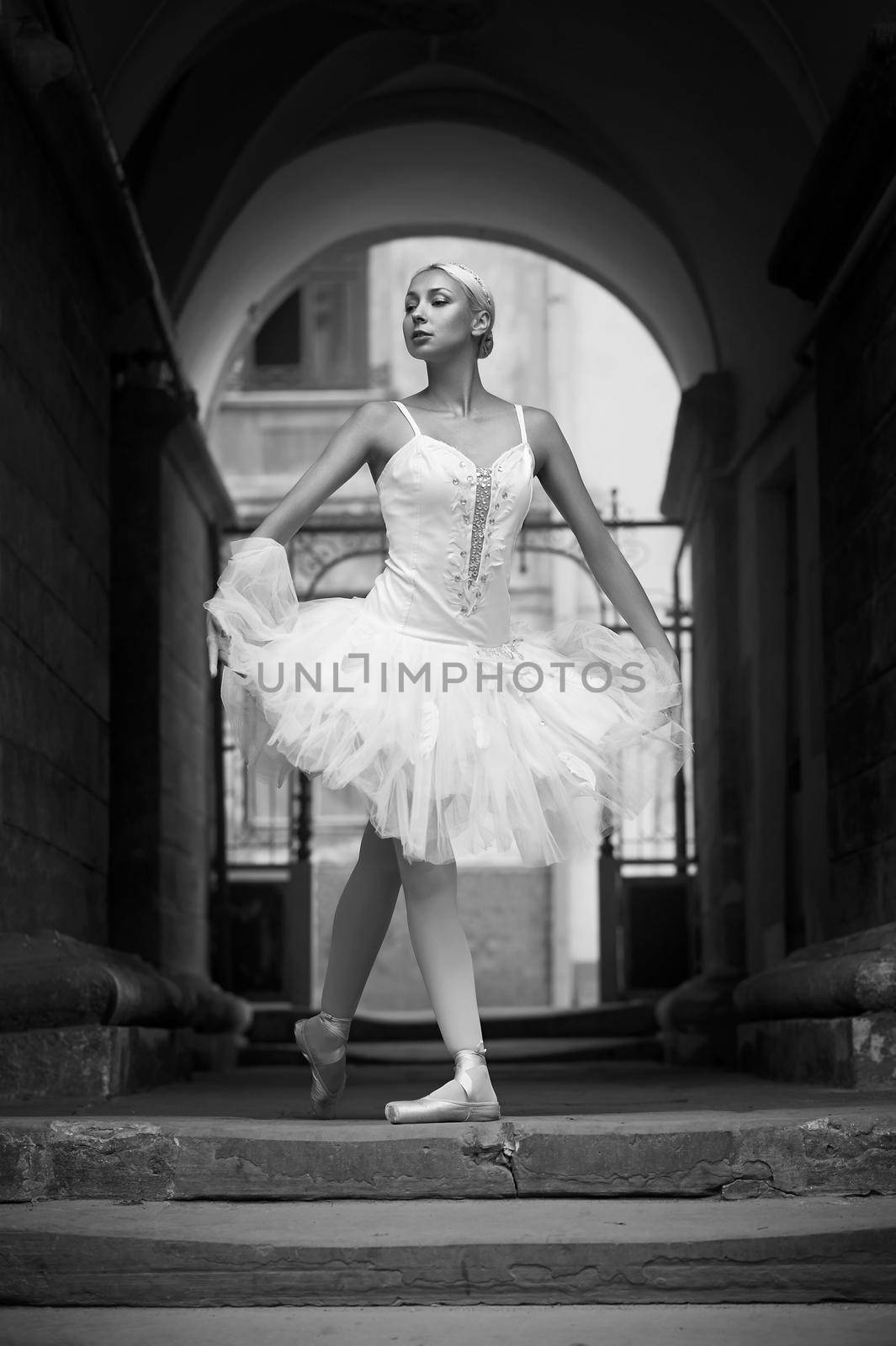 Dancing on the streets. Monochrome portrait of a beautiful ballerina standing in an archway