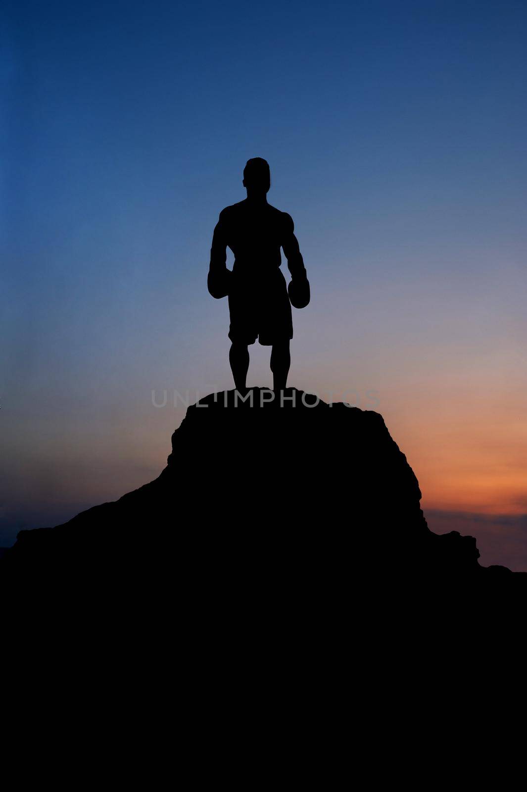 Silhouette of a strong powerful sportsman standing on top of a rock on beautiful sunset copyspace incognito anonymous people lifestyle winner champion leader confidence achieving