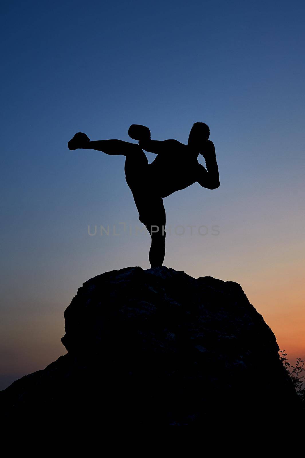 Dark silhouette of a muscular male boxer outdoors on sunset by SerhiiBobyk